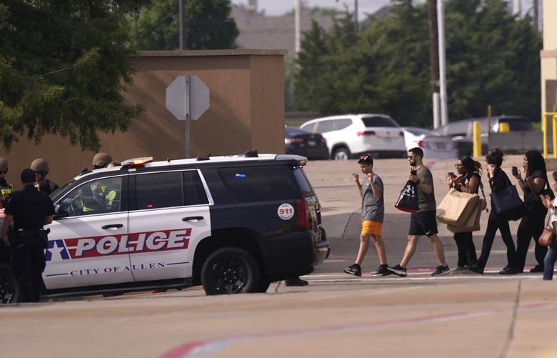 People raise their hands as they leave a shopping center following reports of a shooting, Saturday, May 6, 2023, in Allen, Texas. (AP Photo/LM Otero) TXMO101 TXMO101