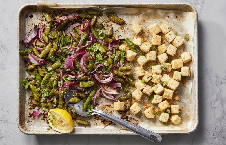 Crispy baked tofu with sugar snap peas in New York, March 28, 2023. A lacy crust of grated Parmesan makes sheet-pan tofu even crispier, Melissa Clark writes. Food styled by Simon Andrews. (Christopher Testani/The New York Times) XNYT81 XNYT81
