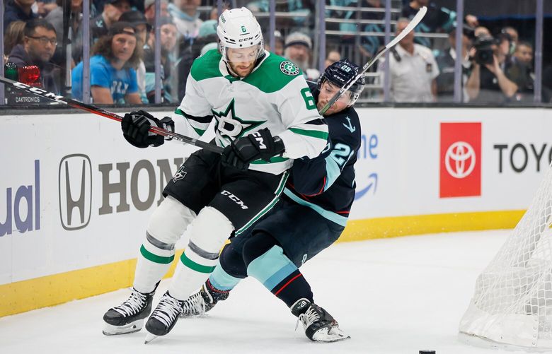 Dallas Stars defenseman Colin Miller ties up Seattle Kraken defenseman Vince Dunn as they vie for the puck behind the net during the first period. 223738