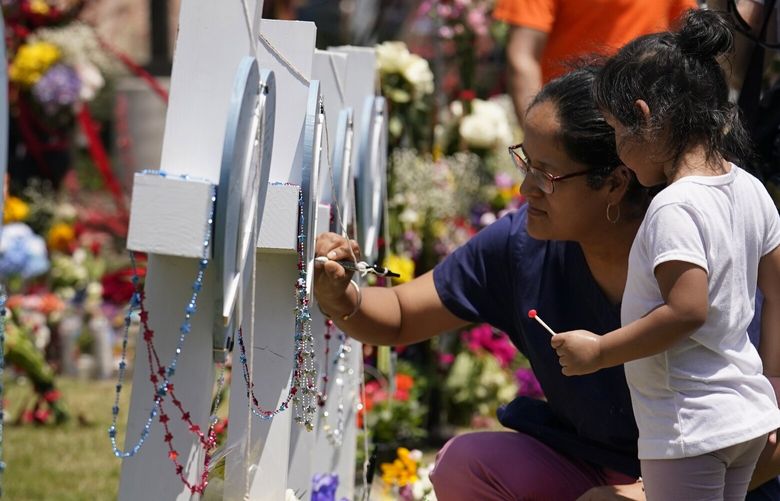 A woman signs a cross as a child looks on at a makeshift memorial by the mall where several people were killed in Saturday’s mass shooting, Monday, May 8, 2023, in Allen, Texas. (AP Photo/Tony Gutierrez) TXTG114 TXTG114