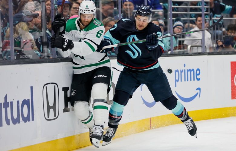 Seattle Kraken center Yanni Gourde puts Dallas Stars defenseman Colin Miller into the boards as the puck bounces away during the first period. 223802