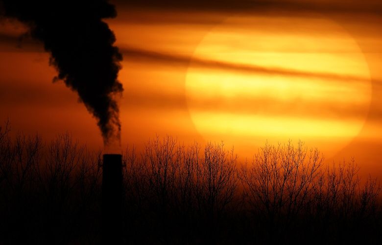 Emissions from a coal-fired power plant are silhouetted against the setting sun, Monday, Feb. 1, 2021, in Kansas City, Mo. (AP Photo/Charlie Riedel)