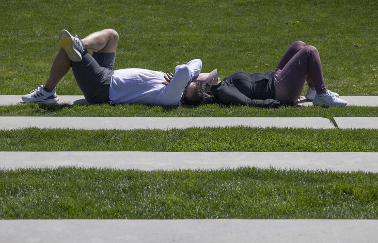 Prashamp Mishra (l) and Rupal Shirpurkar relax in Downtown Park in Bellevue Thursday, May 11, 2023.  They were out enjoying the sunshine.  Temperatures will continue rising this week and should be in the high 80’s on Monday. 223830