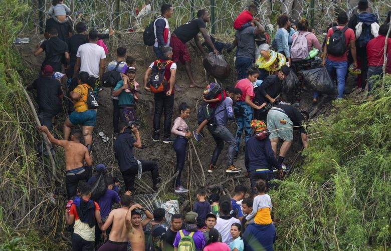 Migrants stand on the bank of the Rio Grande river as Texas National Guards block them from behind razor wire, seen from Matamoros, Mexico, Thursday, May 11, 2023. Pandemic-related U.S. asylum restrictions, known as Title 42, are to expire May 11. (AP Photo/Fernando Llano) XMC110 XMC110