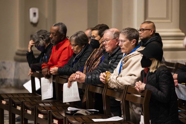 Prayers are offered at St. James Cathedral for homeless people who died in 2022. (Daniel Kim / The Seattle Times)