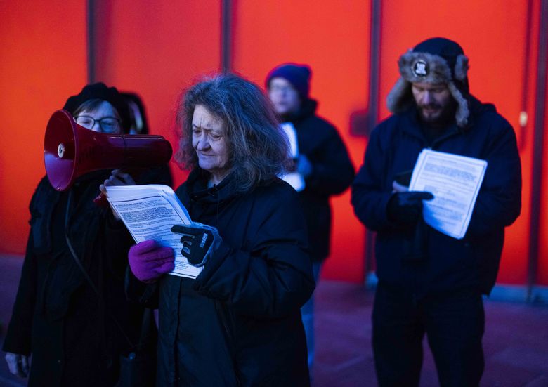 Anitra Freeman reads the names of homeless people who died in 2022. The Women in Black vigil took place outside Seattle City Hall in December. (Daniel Kim / The Seattle Times)