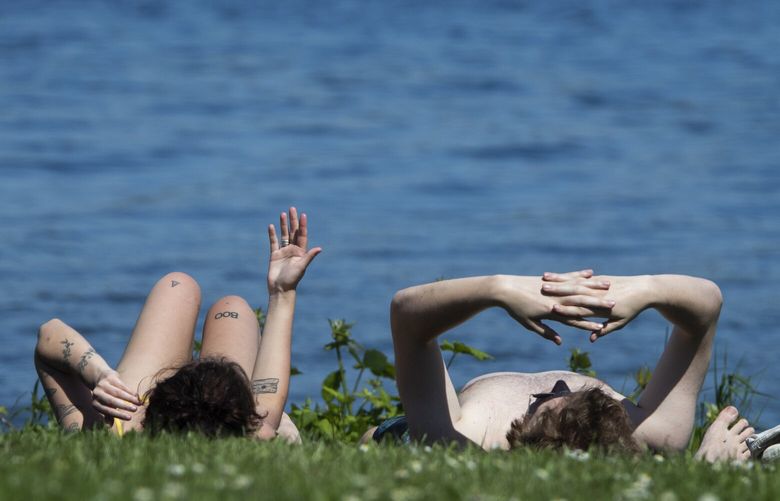 Autumn Rodewald (l) and Connor Sarles, both of Seattle, relax and soak up the rays at a park along Lake Washington Blvd. S. and S. Adams St.  in Seattle Friday, May 12, 2023.  Temperatures in Seattle  the next five days are predicted to be in the 80’s. 223830