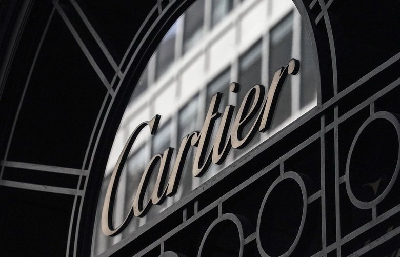 A Cartier sign hangs on the side entrance to its 5th Avenue building Feb. 27, 2023, in New York. Cartier took an image down from its website that showed Indigenous children playing in a field of tall, green grass. The French luxury jewelry brand said it was working to promote the culture of the Indigenous people and protect the rainforest. (AP Photo/Bebeto Matthews) 