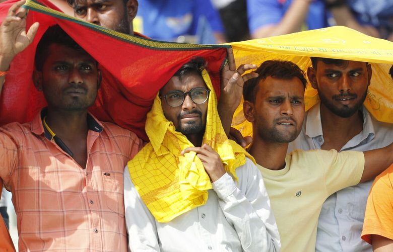 FILE – Cricket fans cover their heads with a long scarf to shield themselves from heat during an Indian Premier League (IPL) cricket match in Lucknow, India, April 22, 2023. A searing heat wave in parts of southern Asia in April this year was made at least 30 times more likely by climate change, according to a rapid study by international scientists released Wednesday, May 17. (AP Photo/Surjeet Yadav, File) CLI401 CLI401