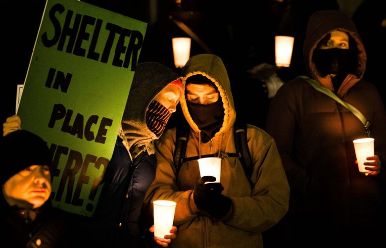 Community members gather outside city hall during a Women in Black candlelight solstice vigil remembering the homeless who died in the 2022, outside of Seattle City Hall on Dec. 21, 2022.