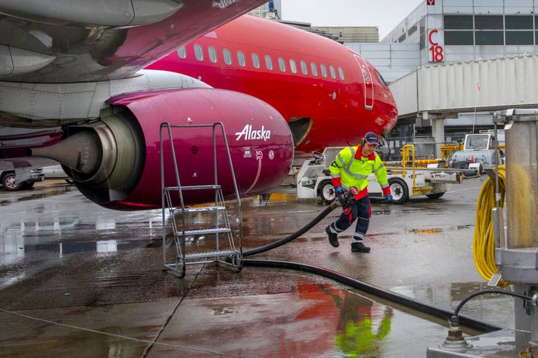 Amer Halilovic, working as a fueling agent, pulls a hose back to a hydrant cart (at right) after refueling an Alaska Airlines jet at Sea-Tac International Airport on Jan. 10, 2020. Dutch company SkyNRG has announced plans to build a massive sustainable aviation fuel refinery in Washington. (Ellen M. Banner / The Seattle Times)