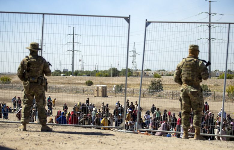 FILE – Migrants wait in line adjacent to the border fence under the watch of the Texas National Guard to enter into El Paso, Texas, Wednesday, May 10, 2023. U.S. authorities say an 8-year-old girl died Wednesday, May 17,  in Border Patrol custody, a rare occurrence that comes as the agency struggles with overcrowding. The Border Patrol had 28,717 people in custody on May 10, the day before pandemic-related asylum restrictions expired, which was double from two weeks earlier, according to a court filing. (AP Photo/Andres Leighton, File) NYCD501 NYCD501
