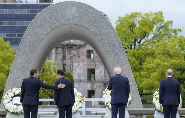 President Emmanuel Macron, left, of France gestures to Prime Minister Fumio Kishida of Japan after laying a wreath at the Hiroshima Peace Memorial Park with U.S. President Joe Biden and Chancellor Olaf Scholz, right, of Germany in Hiroshima, Japan, Friday, May 19, 2023, during the G7 Summit. (AP Photo/Susan Walsh,Pool) JPNW512 JPNW512