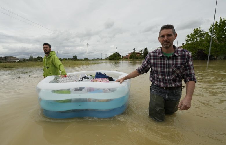 People use a plastic portable pool to carrie bags and personal effects in a flooded road of Lugo, Italy, Thursday, May 18, 2023. Exceptional rains Wednesday in a drought-struck region of northern Italy swelled rivers over their banks, killing at least eight people, forcing the evacuation of thousands and prompting officials to warn that Italy needs a national plan to combat climate change-induced flooding. (AP Photo/Luca Bruno) XAC109 XAC109