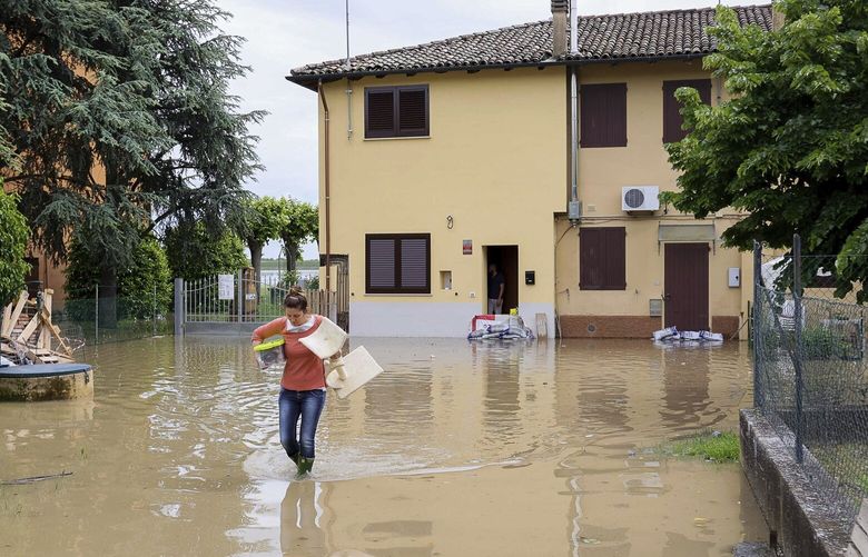 A woman carries her belongings in a flooded area near Bologna, Italy, Thursday, May 18, 2023. Rescue crews worked Thursday to reach towns and villages in northern Italy that were cut off from highways, electricity and cell phone service following heavy rains and flooding, as farmers warned of “incalculable” losses and authorities began mapping out cleanup and reconstruction plans. (Guido Calamosca/LaPresse via AP) BOL803 BOL803