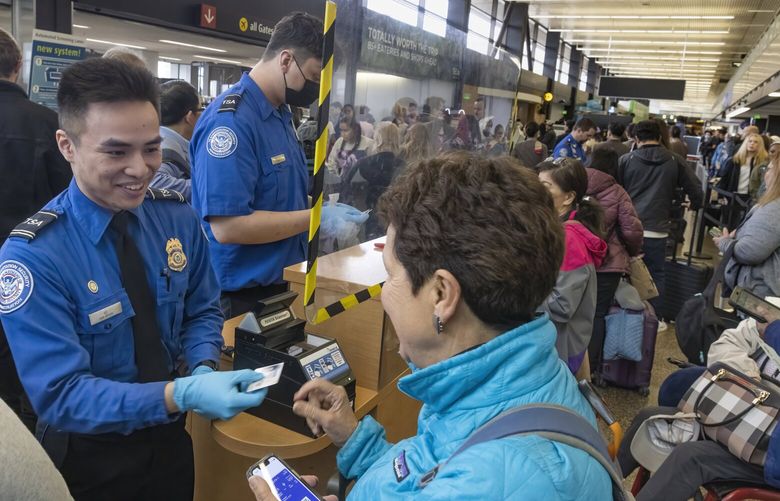 Aaron Vo, a first line supervisor and lead TSA officer at SEA (Seattle-Tacoma International Airport) checks a passenger’s ID at a security checkpoint at the airport.

This is for a “behind the scenes” at SEA, shot Monday, April 3, 2023 for a Pacific magazine story.
 223365.  001