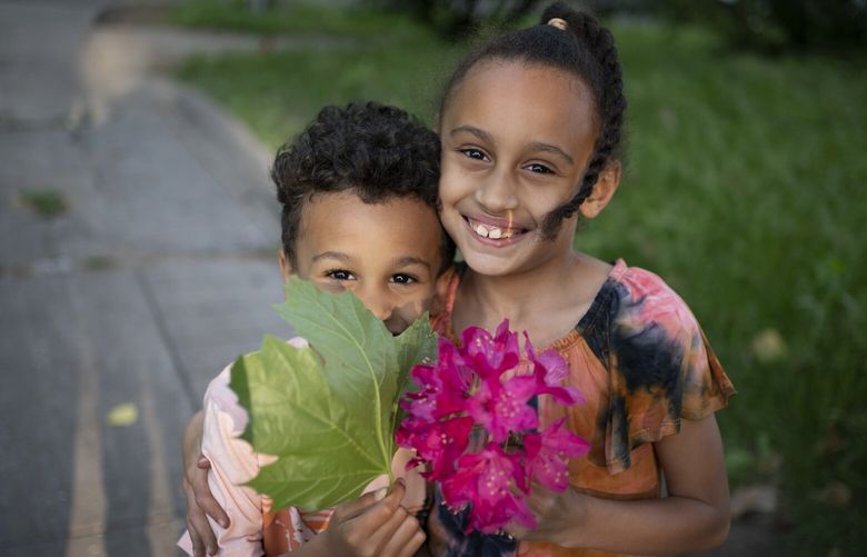 Caydence Manson and her brother, Carter Manson, hold flowers and leaves they found in the garden as they pose for a portrait in Hartford, Conn., on Wednesday, May 25, 2022. The Manson children have dreams – Caydence wants to be an architect, Carter loves sports and hopes to grow up to be an athlete. But for now, they struggle to breathe. (AP Photo/Wong Maye-E) NYWM620 NYWM620