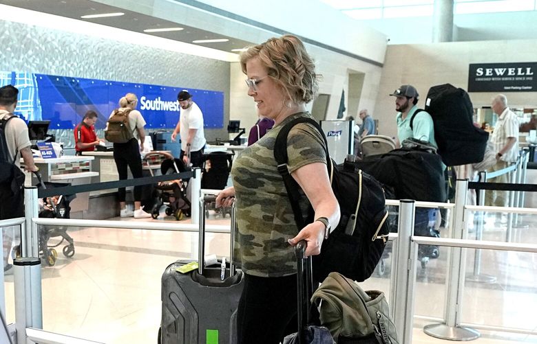 Bethany Adleta, center, of Frisco, Texas, makes her way to the ticketing gate as she prepares to travel out of Love Field airport, Friday, May 19, 2023, in Dallas. Fees, higher fares and fewer discounts for military veterans are causing Adleta to debate flying versus driving if she makes any more trips this summer. (AP Photo/Tony Gutierrez) TXTG103 TXTG103