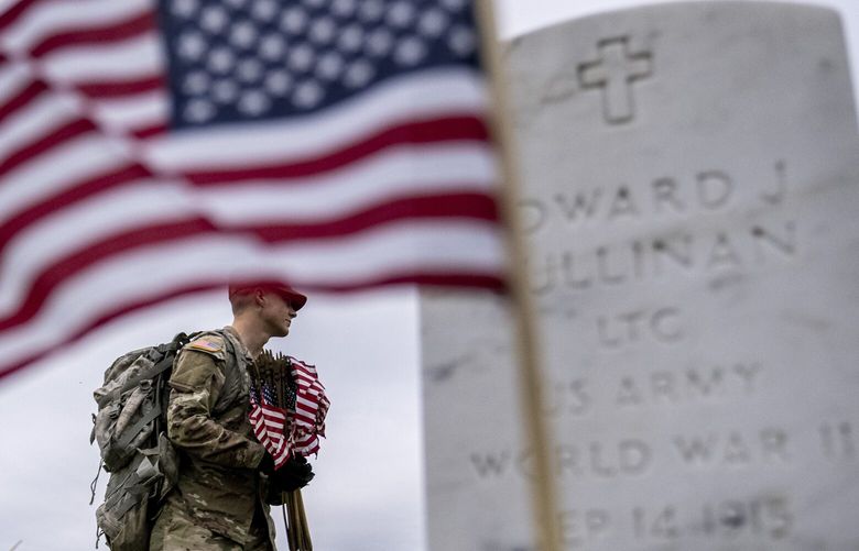 A member of the 3rd U.S. Infantry Regiment also known as The Old Guard, places flags in front of each headstone for “Flags-In” at Arlington National Cemetery in Arlington, Thursday, May 25, 2023, to honor the Nation’s fallen military heroes ahead of Memorial Day. (AP Photo/Andrew Harnik) VAAH112 VAAH112