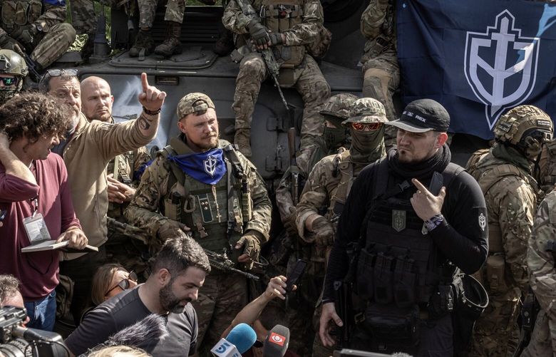 Denis Kapustin, at right in black, the leader of an anti-Putin group of ethnic Russians who has been identified as a neo-Nazi by the Anti-Defamation League, is interviewed and photographed by reporters in the northeastern Ukraine, May 24, 2023. Many of the fighters who led an incursion into Russian territory this week have espoused far-right views and have neo-Nazi ties. (Finbarr O’Reilly/The New York Times) XNYT0889 XNYT0889