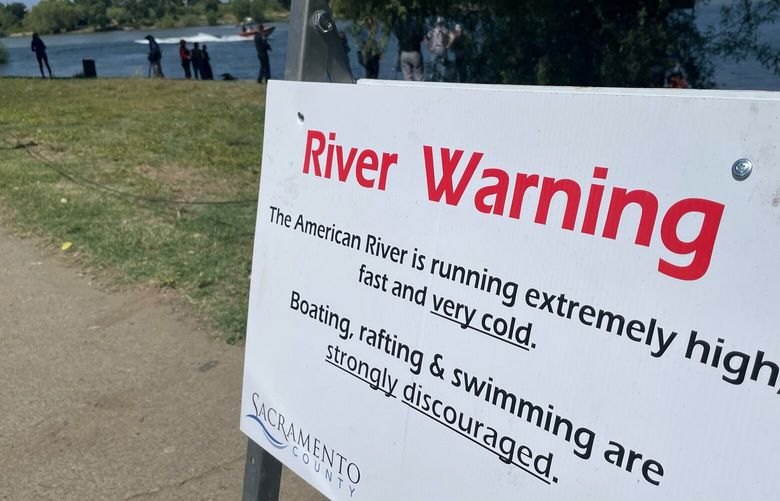 A sign warning the public of dangerous river conditions is posted alongside the American River in Sacramento, Calif., Tuesday, May 23, 2023. California rivers fed by winter’s massive Sierra Nevada snowpack have been turned into deadly torrents, drawing warnings from public safety officials ahead of the Memorial Day weekend and the traditional start of outdoor summer recreation. (AP Photo/Haven Daley)