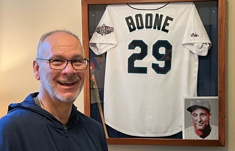 Bill Boone, who has been diagnosed with ALS (often called Lou Gehrig’s disease) poses in front of a Mariners jersey at his home in Mukilteo. An image of Gehrig, the Yankees great who died from ALS, is in the lower right corner.