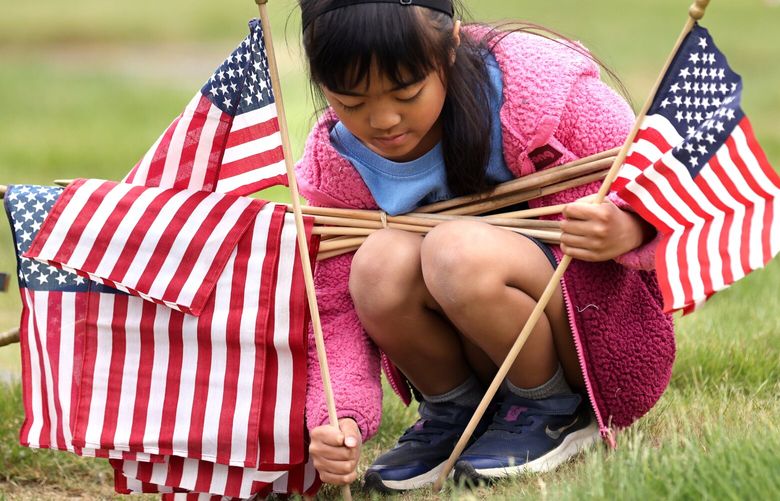 Riley Rose Tabladillo, 6 yrs., from the Amercian Heritage Girls helps place flags on the graves of veterans at Purdy & Walters at Floral Hills Funeral Home & Cemetery in Lynnwood on Saturday, May 27, 2023.