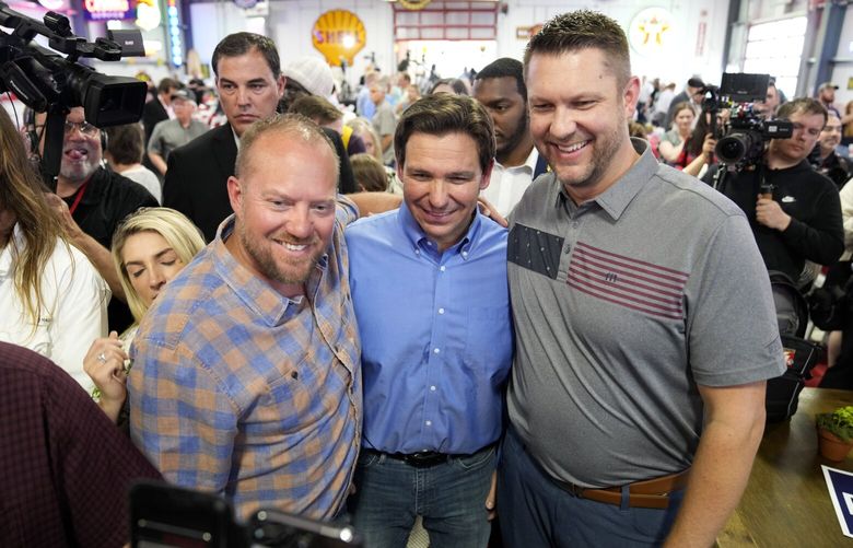 FILE – Florida Gov. Ron DeSantis, center, poses for a photo with audience members during a fundraising picnic forRep. Randy Feenstra, R-Iowa, May 13, 2023, in Sioux Center, Iowa. DeSantis is kicking off his presidential campaign in Iowa at the start of a busy week that will take him to 12 cities in three states as he tests his pitch as the most formidable Republican challenger to former President Donald Trump. (AP Photo/Charlie Neibergall. File) WX201 WX201