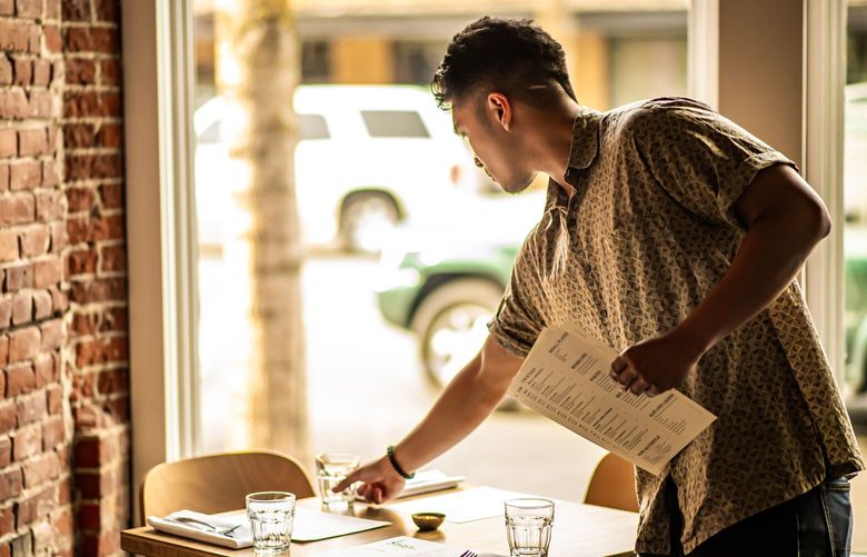 Host Fabian Aquino sets tables at The Black Cypress with menus in preparation for service at The Black Cypress. (Courtesy of Lance Lee)