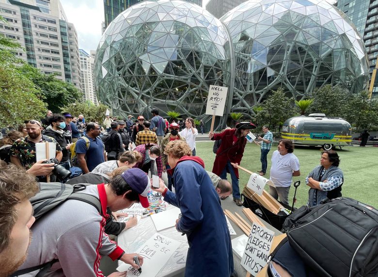 A group of Amazon employees make placards in Seattle as they participate in a walkout Wednesday outside Amazon’s Seattle headquarters. The protest is meant to show employees’ frustration with layoffs, returning to the office and what they view as a lack of action on climate change.  (Ken Lambert / The Seattle Times)