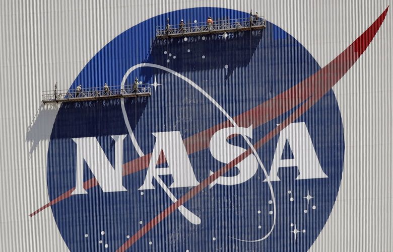 FILE – Workers on scaffolding repaint the NASA logo near the top of the Vehicle Assembly Building at the Kennedy Space Center in Cape Canaveral, Fla., May 20, 2020.  (AP Photo/John Raoux, File) NYPS201 NYPS201