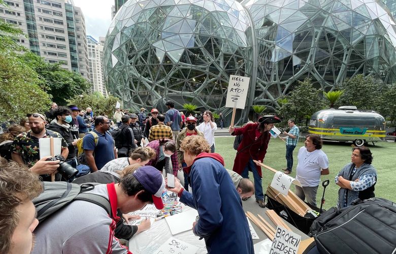 A group of Amazon employees make placards in Seattle as they demonstrate by walking off the job Wednesday to show frustration with layoffs, returning to the office, and a lack of action on climate change.