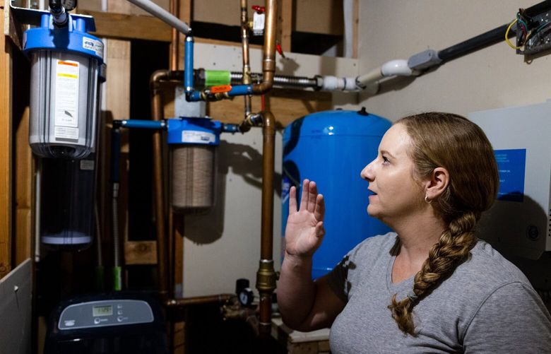 Jenna Vogel looks at her family’s water filtration system in their home in Selah, Wash., on Friday, May 19, 2023. They opted to install the system themselves and while it filters out much of the PFAS, it’s extremely costly and they have to replace the filter every couple of months.