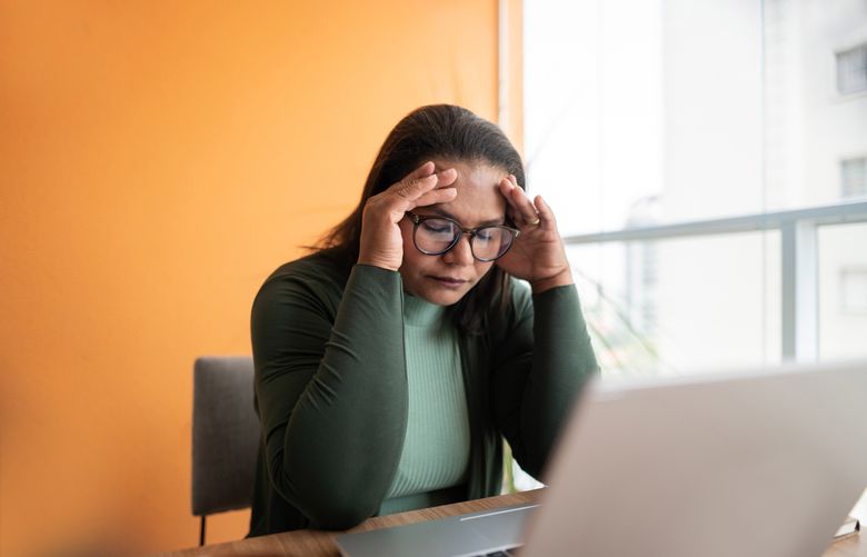 Tired mature woman with headache working at home
