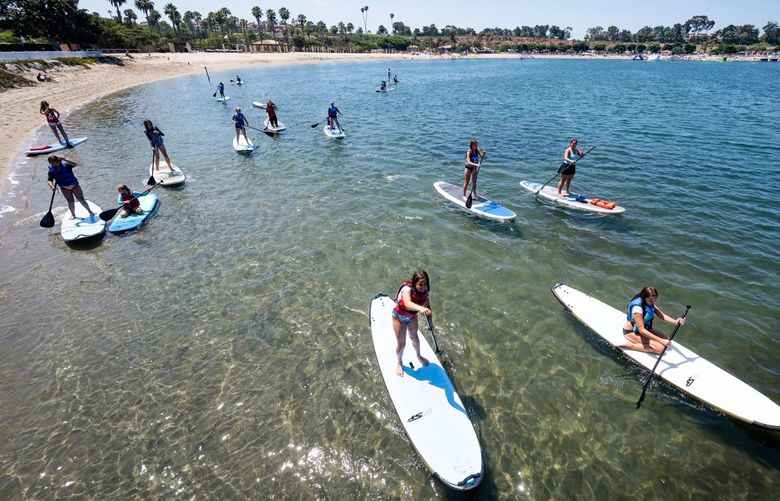 Campers make their way around the lagoon at Newport Dunes in Newport Beach, Calif., in 2022. Pirate Coast Paddle Company introduced the campers to stand up paddle boarding during the Kid’s Pirate Paddle Camp. (Paul Bersebach/The Orange County Register/TNS)