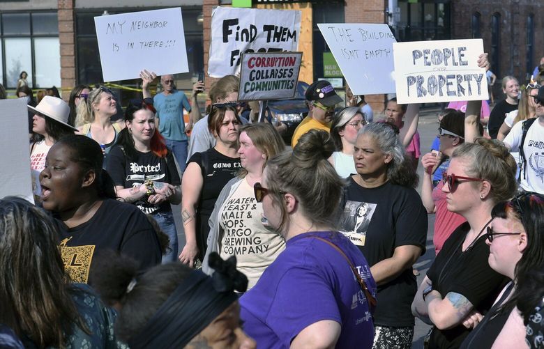 Protesters stand outside of Davenport City hall as rescuers enter the partially collapsed apartment building, The Davenport, 324 Main St., to remove tenants pets, Tuesday, May 30, 2023, in Davenport, Iowa. Five residents of a six-story apartment building that partially collapsed in eastern Iowa remained unaccounted for Tuesday, and authorities feared at least two of them might be stuck inside rubble that was too dangerous to search. (Gary Krambeck/Quad City Times via AP) IADAV105 IADAV105