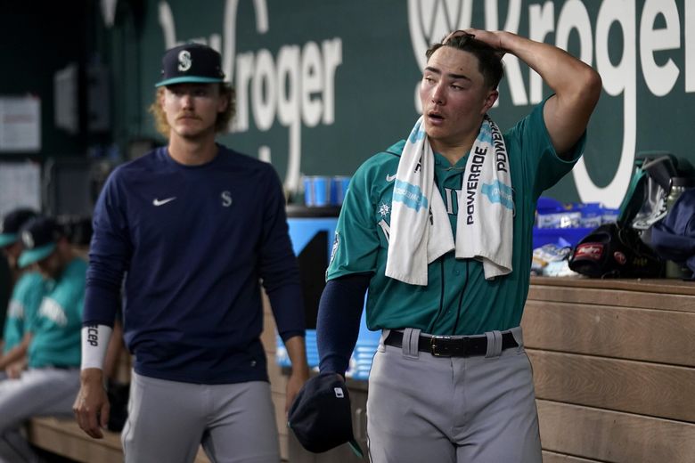 Seattle Mariners starting pitcher Bryan Woo, right, walks through the dugout as he talks with Bryce Miller, left, after working against the Texas Rangers in the second inning Saturday. Woo threw two innings in his major league debut Saturday. (Tony Gutierrez / The Associated Press)