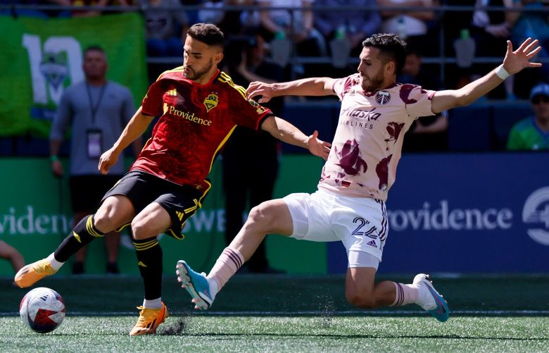 Seattle Sounders FC midfielder Cristian Roldan crosses the ball past a lunging Portland Timbers midfielder Cristhian Paredes during the second half. 224067