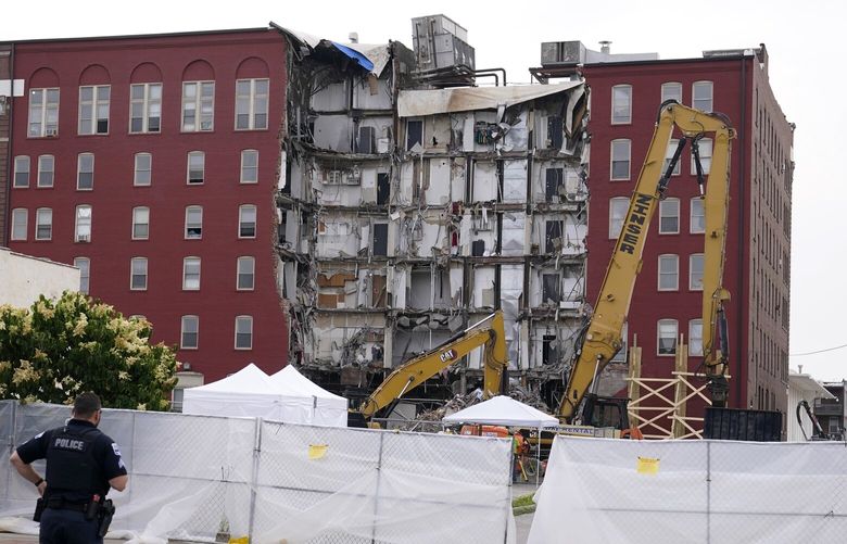 A police officer stands in the street near the site of a collapsed apartment building, Monday, June 5, 2023, in Davenport, Iowa. The six-story, 80-unit building partially collapsed May 28. (AP Photo/Charlie Neibergall) IACN101 IACN101