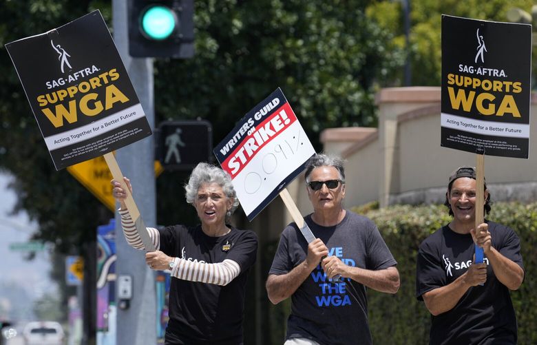 Actors Amy Aquino, left, and Michael Kajganich, right, join writer Steve Skrovan in a Writers Guild rally outside Warner Bros. Studios, Monday, May 22, 2023, in Burbank, Calif. (AP Photo/Chris Pizzello) 