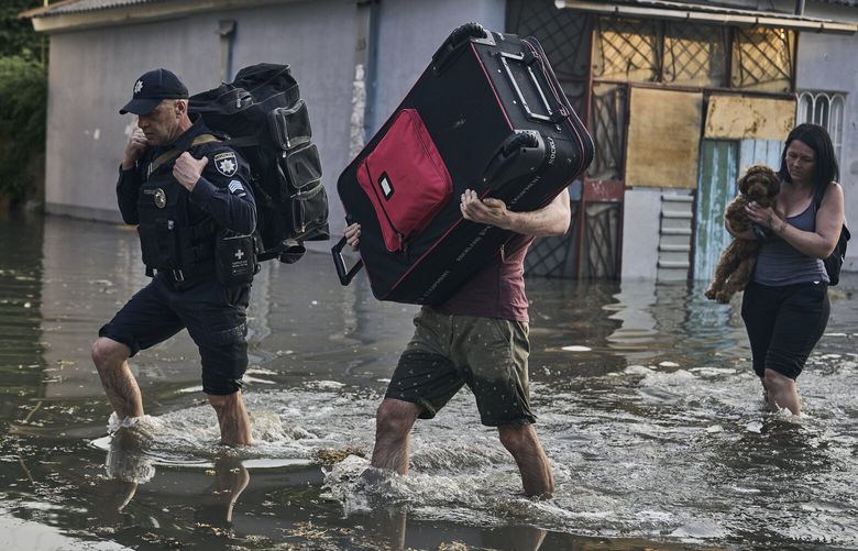 Local residents carry their belongs as they evacuated from a flooded neighborhood in Kherson, Ukraine, Tuesday, June 6, 2023. The wall of a major dam in a part of southern Ukraine has collapsed, triggering floods, endangering Europe’s largest nuclear power plant and threatening drinking water supplies. (AP Photo/Libkos) XEL145 XEL145