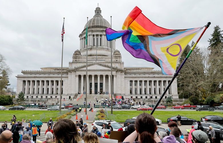 A supporter of trans rights waves a flag in front of the Temple of Justice as an opposing rally for opponents of legislation to exempt youth shelters from contacting parents of kids seeking gender affirming health care gathers on the steps of the Capitol Building Friday, April 21, 2023 in Olympia, Wash. 223644