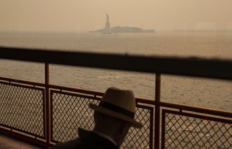FILE – The Statue of Liberty, covered in a haze-filled sky, is photographed from the Staten Island Ferry, June 7, 2023, in New York. Thick, smoky air from Canadian wildfires made for days of misery in New York City and across the U.S. Northeast this week. But for much of the rest of the world, breathing dangerously polluted air is an inescapable fact of life — and death. (AP Photo/Yuki Iwamura, File) CLI805 CLI805