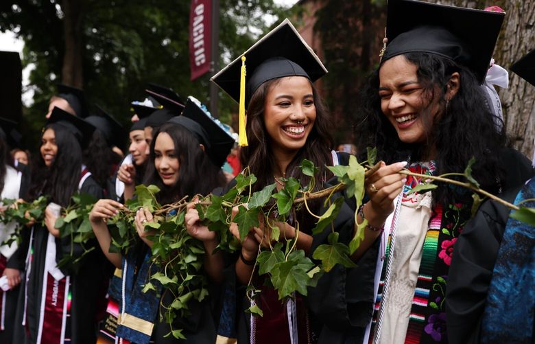 Brenda Ramirez-Sanchez, a business administration graduate, right, and Jocelyne Gaytan, a psychology and sociology graduate, second from right, attend Seattle Pacific University’s Ivy Cutting ceremony in Seattle Friday, June 9, 2023. Hundreds of undergraduates were given their own sprig of ivy that symbolizes their connection and release from SPU. The tradition has been part of graduation festivities since 1922. 224142