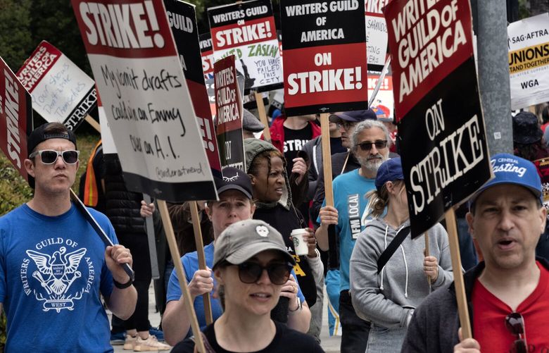 Picketers pass near a studio entrance during a Writers Guild rally outside Warner Bros. Studios, Wednesday, May 24, 2023, in Burbank, Calif. (AP Photo/Richard Vogel) 