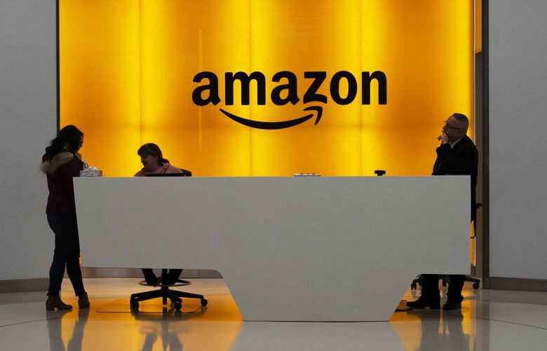 FILE – In this Feb. 14, 2019, file photo people stand in the lobby for Amazon offices in New York. Amazon is kicking off its annual security-focused cloud computing conference on Tuesday amid a slowdown in its profitable cloud business Amazon Web Services, or AWS. (AP Photo/Mark Lennihan, File) NYPM204 NYPM204