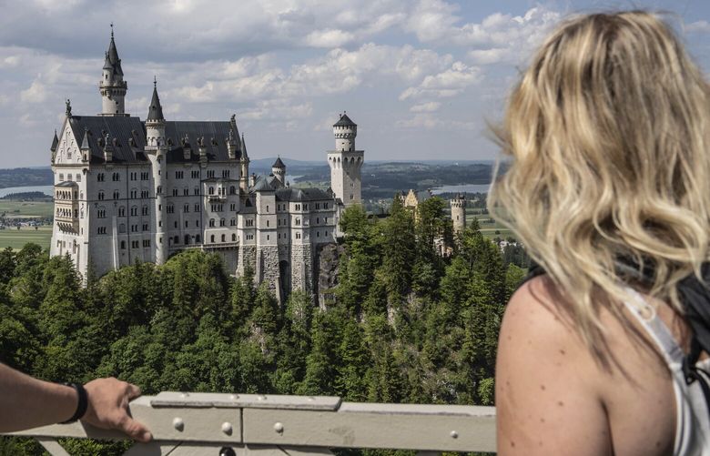 People watch the Neuschwanstein castle, in Schwangau, Germany, Thursday, June 15, 2023. Authorities say an American man has been arrested in Germany after allegedly assaulting two tourists he met near Neuschwanstein castle. The attack, which occurred on Wednesday, left one of the women dead. Police said Thursday that the 30-year-old man met the two women on a hiking path and lured them onto a trail. They said the man then “physically attacked” the younger woman. (Frank Rumpenhorst/dpa via AP) SCH803 SCH803