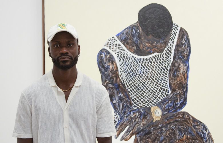 Portrait of Amoako Boafo in front of his artwork. “When people come to see this exhibition, I hope they feel like they are a part of the paintings or that they can imagine themselves as the subjects as these paintings were made,” the artist said in a press release.