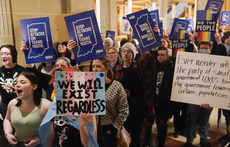 FILE – Protesters stand outside of the Senate chamber at the Indiana Statehouse on Feb. 22, 2023, in Indianapolis. A federal judge is scheduled Wednesday, June 14, to hear arguments in a lawsuit seeking to block an Indiana law banning doctors from providing puberty blockers, hormones and gender-affirming surgeries to minors. (AP Photo/Darron Cummings, File) NY130 NY130