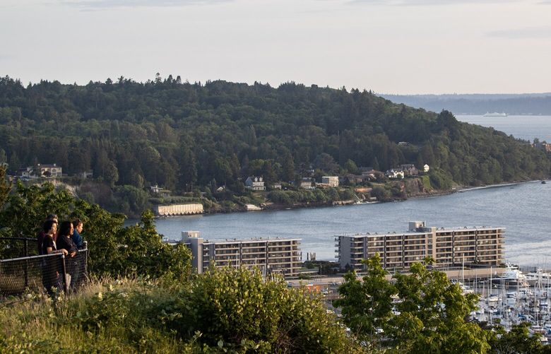 People watch the sun set over the Puget Sound Thursday, June 15, 2023, at Sunset Hill Park in Seattle.